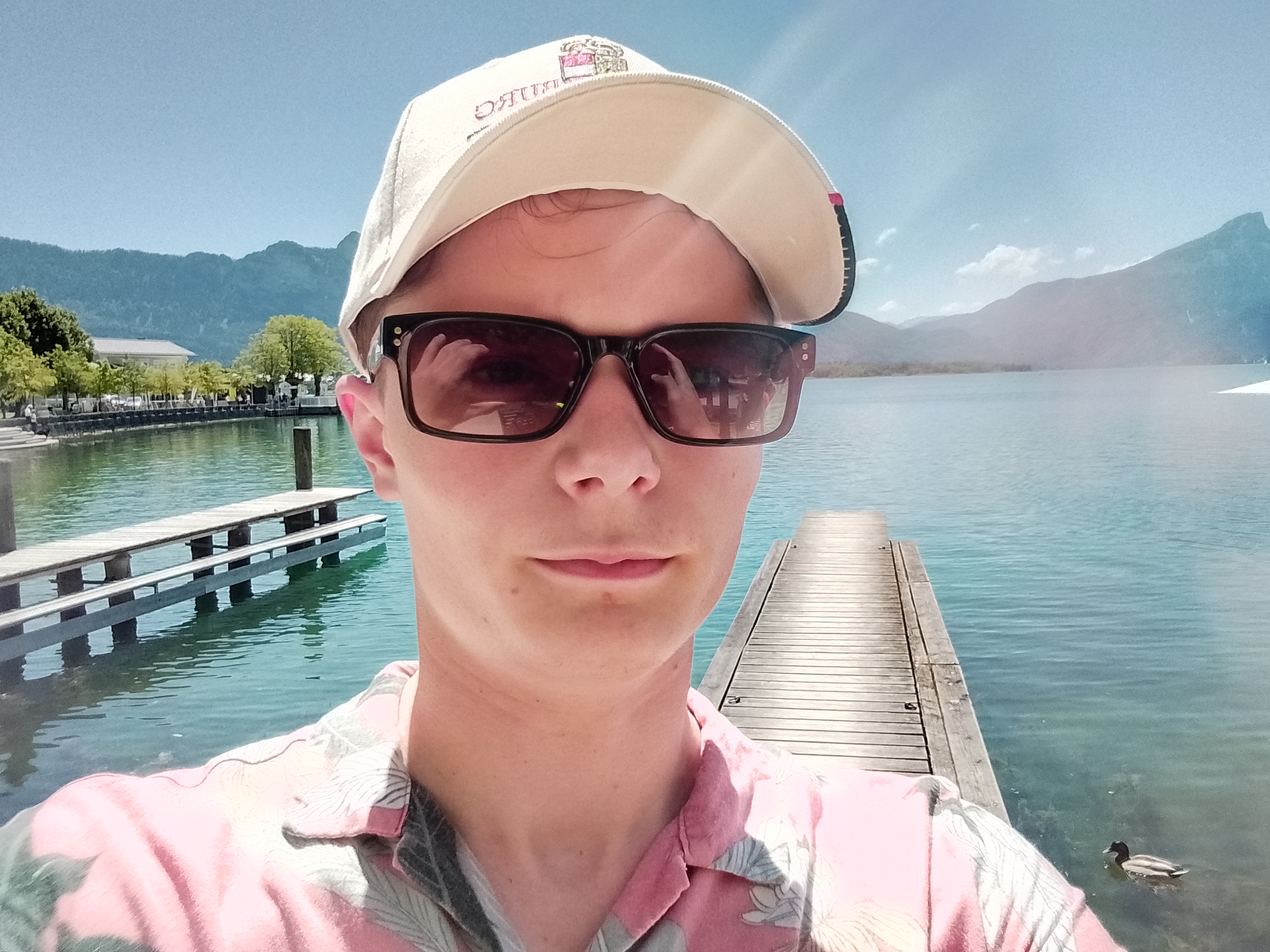 Me, stood in front of a lake with mountains in the background in Austria, duck in the background Me in Austria